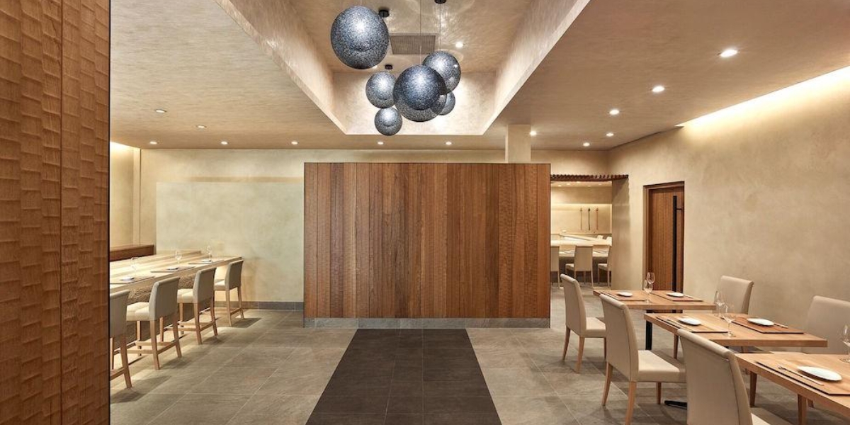An elegant dining room with wood paneling, sculptural pendant lighting, and warm neutral tones showcasing the refined interior design of Kenzo Napa.