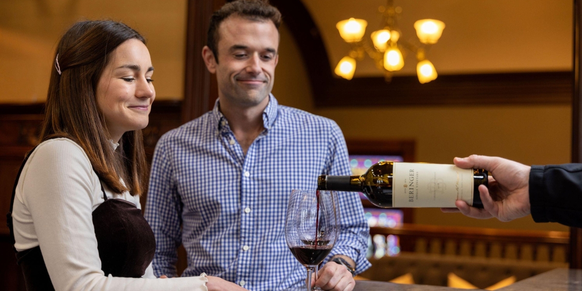 A couple watches red wine being poured in an elegant tasting room, reflecting the cozy charm of st helena tasting rooms - Romantic St. Helena Tasting Rooms and Wineries for Couples.