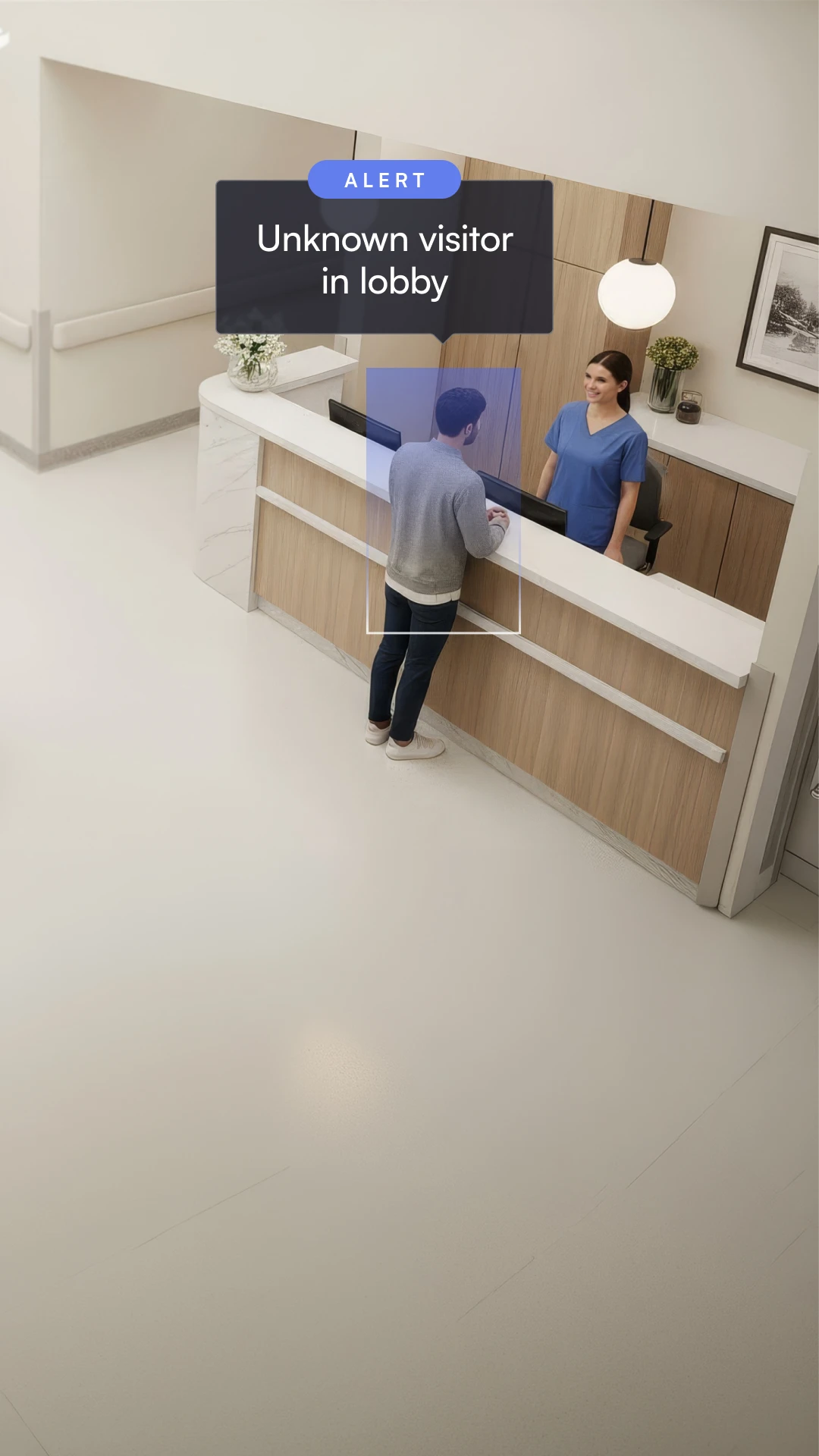 Man standing at a healthcare lobby reception desk talking to a smiling nurse with an alert saying 'Unknown visitor in lobby.'