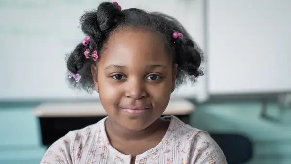 Elementary school student smiling in classroom — portrait headshot.