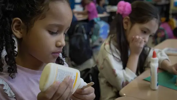 Students working on an arts-and-crafts project with glue during class — candid photo.