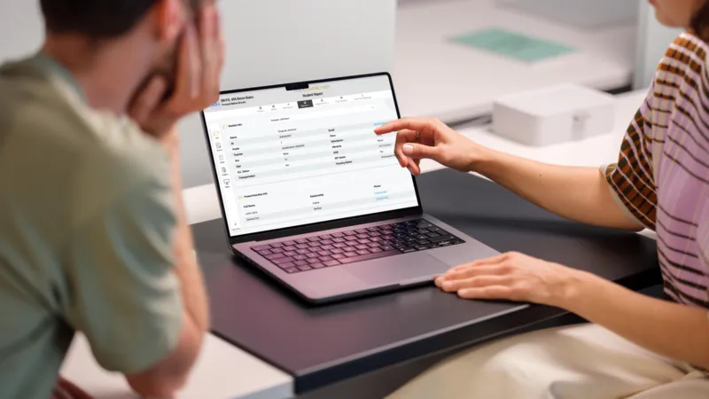 Two colleagues reviewing SOLVED K-12 Data Dashboard student record on a laptop during a planning meeting