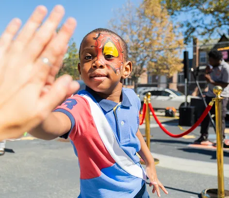 Boy with face paint giving a high five