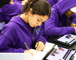 Middle school student sketching in a notebook during art class