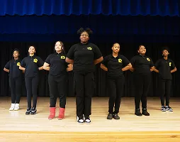School step team performing a routine on stage in coordinated uniforms