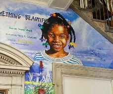 Colorful mural of a smiling child painted inside the school building near the main staircase