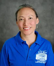 Staff portrait of a smiling team member wearing a blue school polo shirt