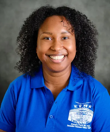 Staff portrait of a smiling school staff member in a blue polo