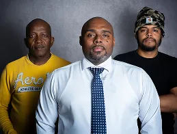 Three staff members posing for a formal group portrait in front of a gray backdrop