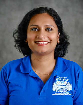A smiling woman with dark wavy hair wearing a blue polo shirt