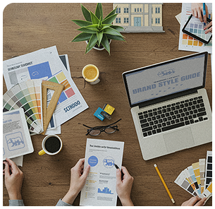 Brand style guide planning with laptop, color palette swatches, and design materials on a wooden desk