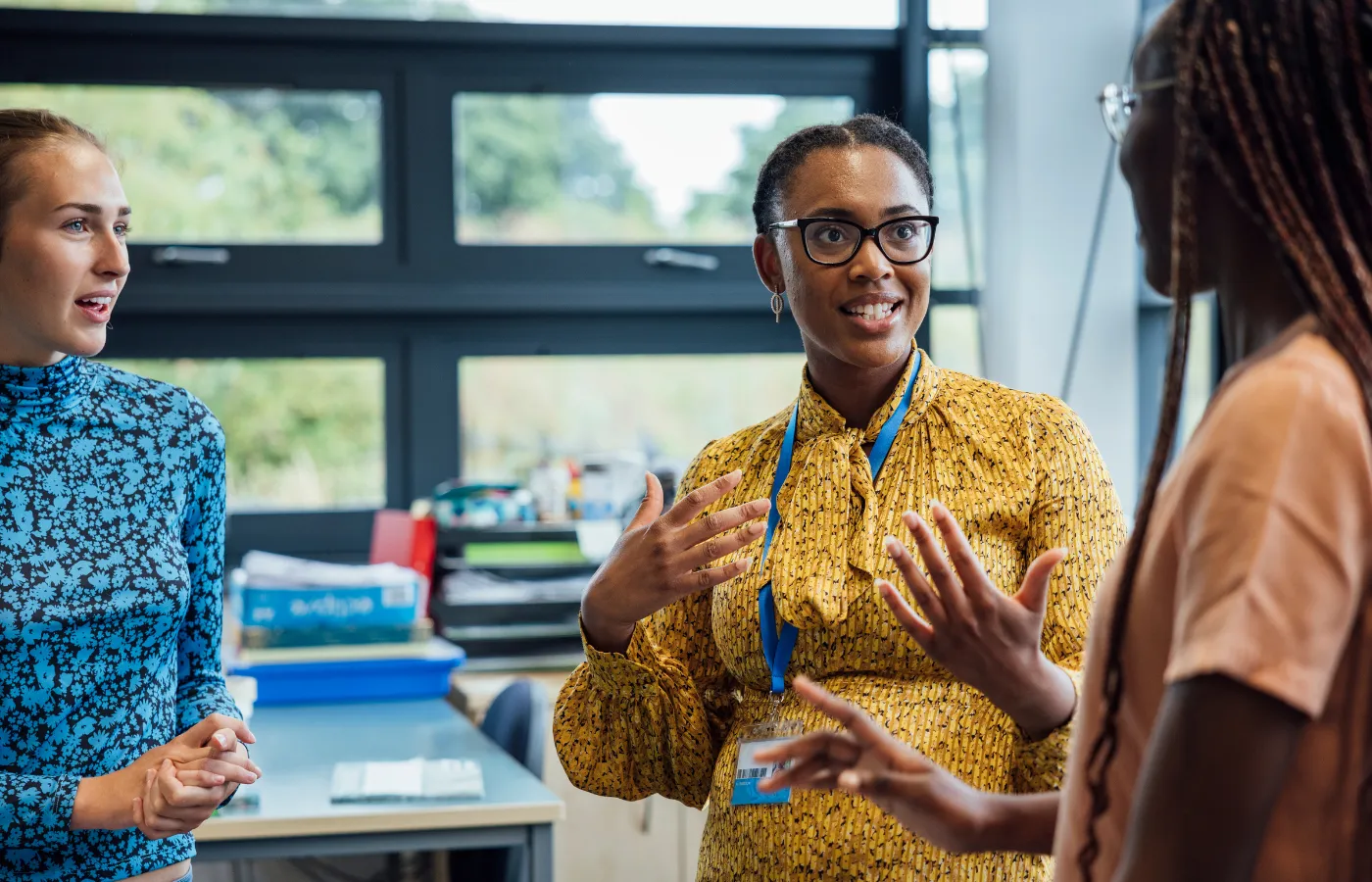 A group of teachers wearing professional attire, gathered in a classroom with name tags, discussing strategies, symbolizing the professional development opportunities provided by SOLVED Consulting.