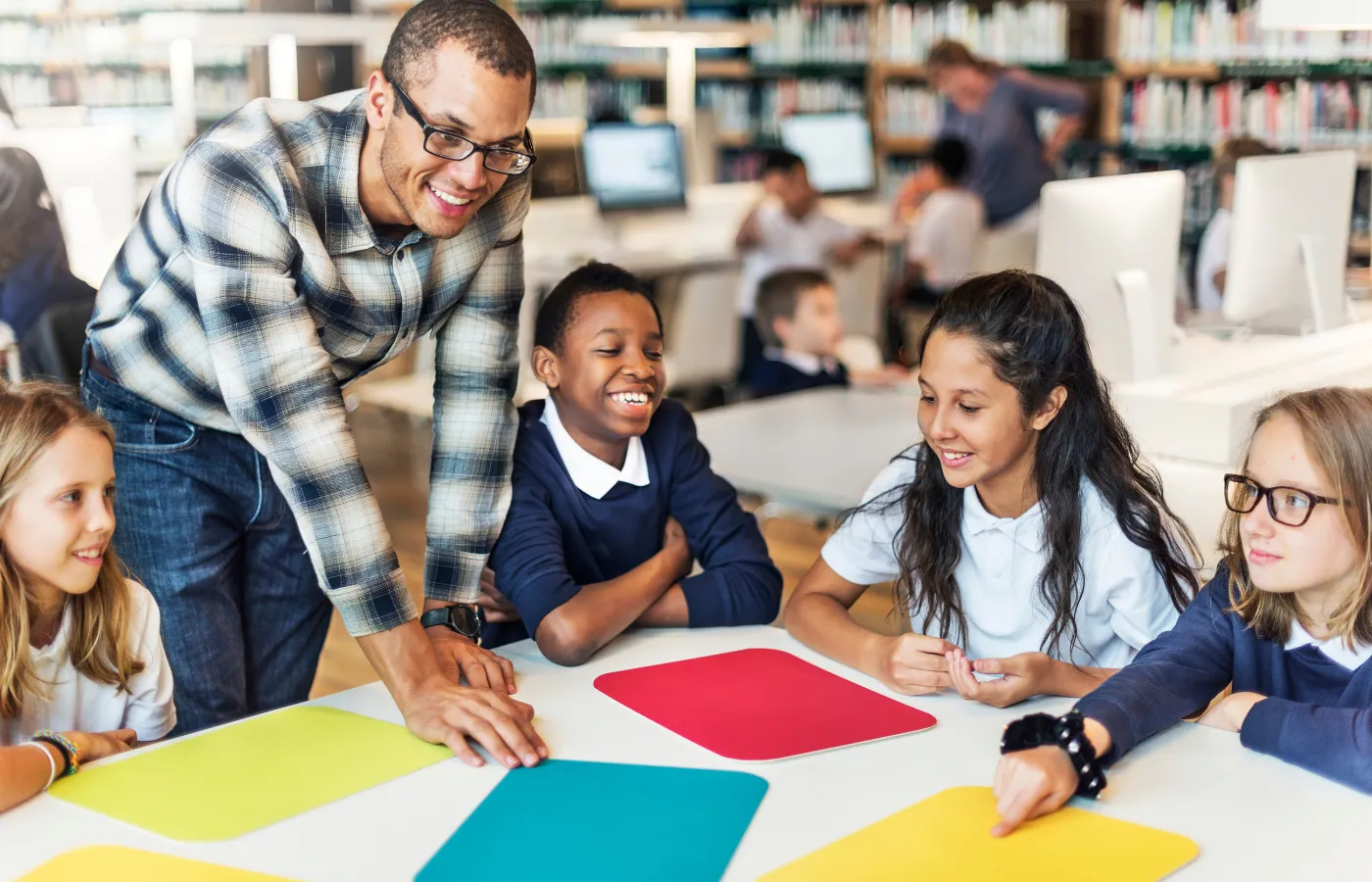 Male teacher engaging with middle school students at a round table, collaboratively discussing examples and non-examples, showcasing group learning with the Frayer Model.