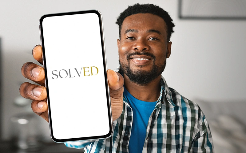Smiling man holding smartphone showing the SOLVED school app screen, promoting parent app downloads.