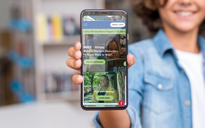 Student holding a smartphone showing a branded school website and app, demonstrating consistent school identity across digital platforms.