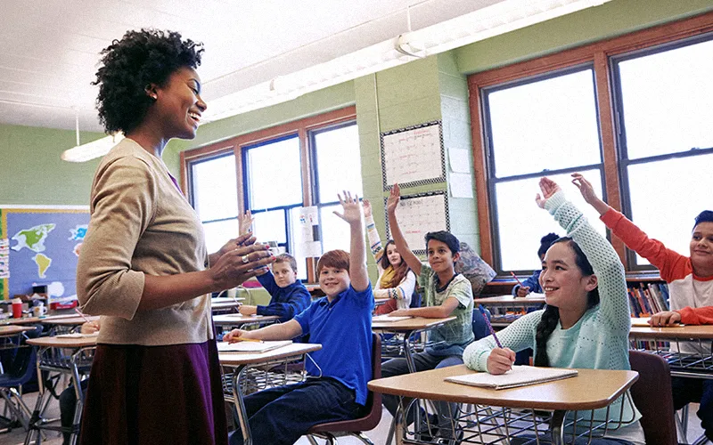 Teacher leads attention routine as students raise hands in an engaged class