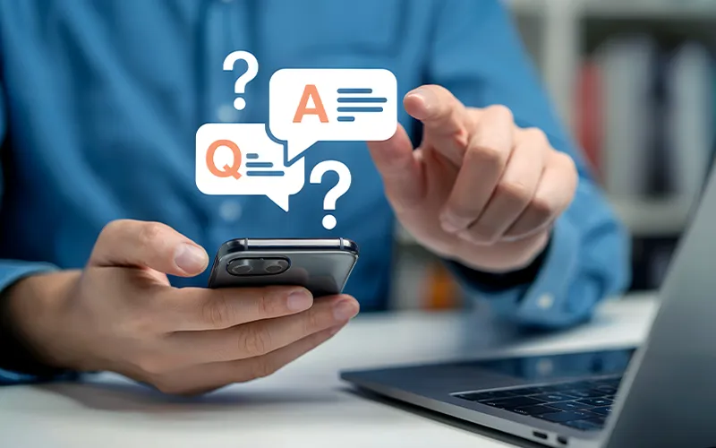 Person holding a smartphone with Q and A chat icons, representing structured literacy walkthrough FAQs and support.