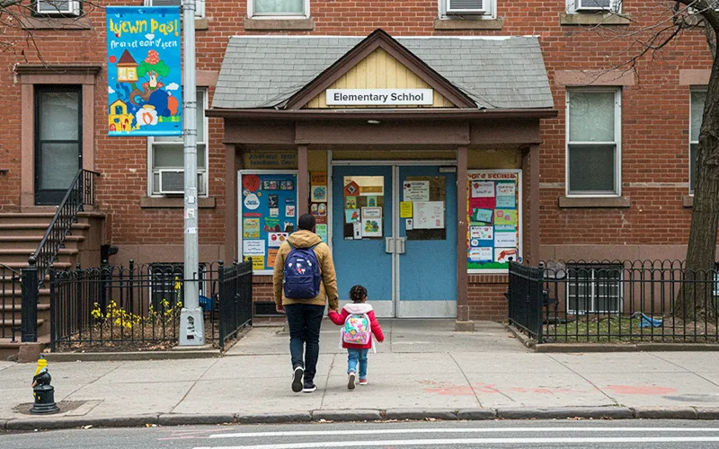 Caregiver walks child to an NYC elementary school during a key admissions transition