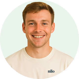 Smiling young man with short light brown hair wearing a white shirt with the word 'nilo' on it.