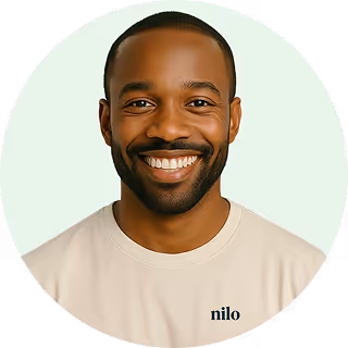 Smiling man with short hair and beard wearing a light beige shirt with the word 'nilo' on it, set against a light background.
