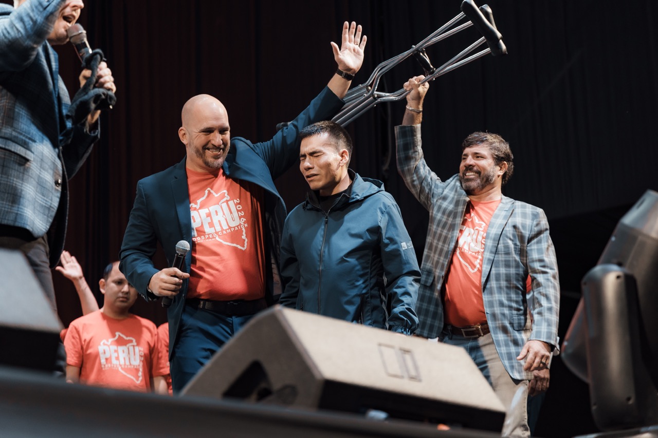 A man raising his crutches on stage as the team celebrates
