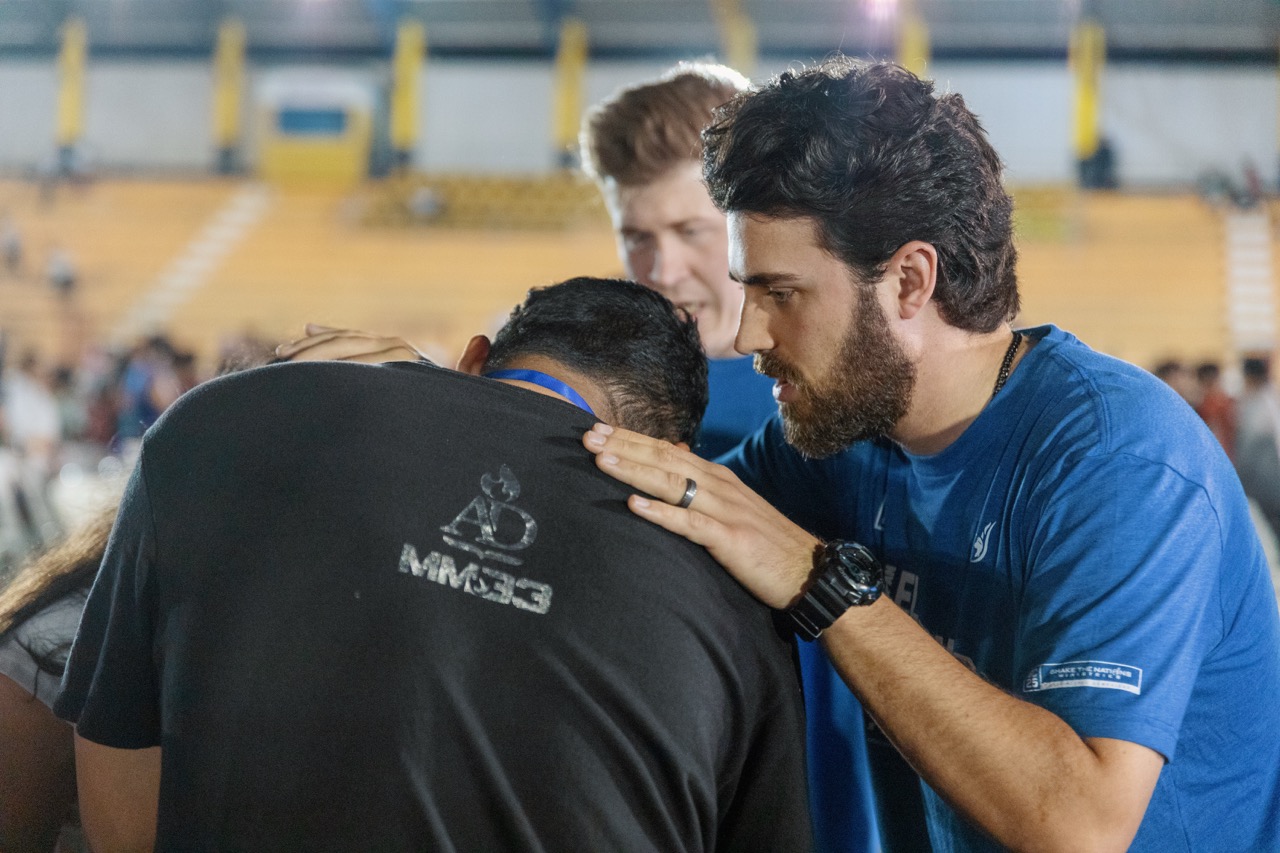 Prayer team members laying hands on a man in prayer