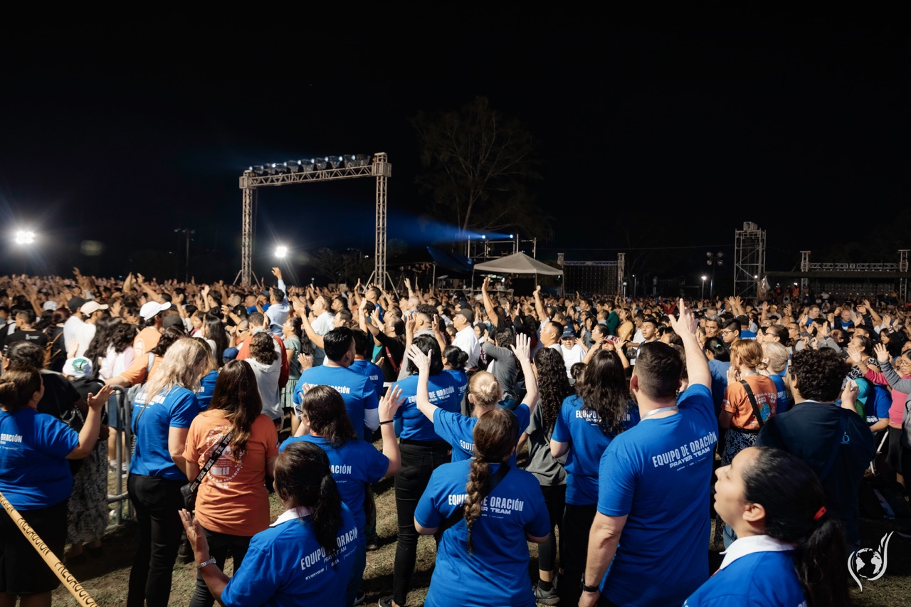 Prayer team members in blue shirts worshipping with the crowd at a campaign in San Salvador