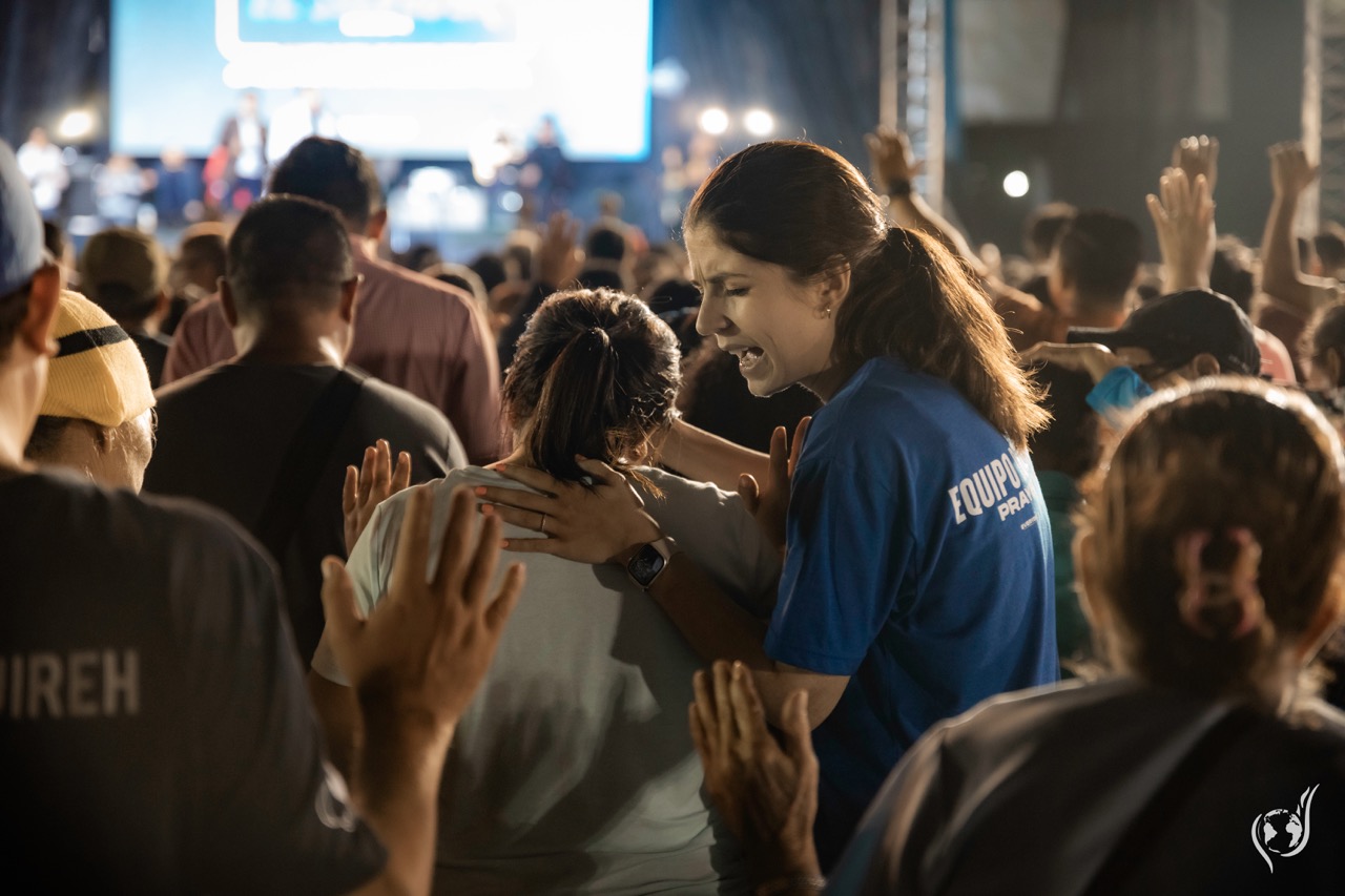 A prayer team member praying over a woman during worship at a Gospel Campaign in San Salvador
