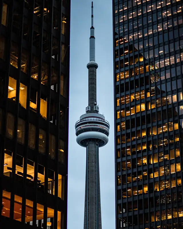 CN Tower in Toronto between illuminated office buildings at dusk