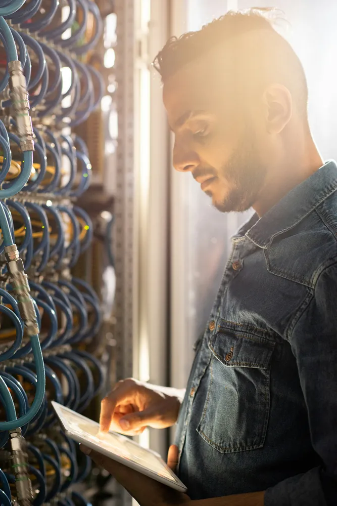 IT engineer reviewing test results on a tablet by a server cabinet