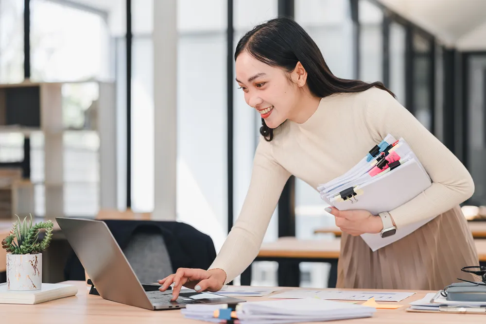 Woman holding a binder and a laptop computer