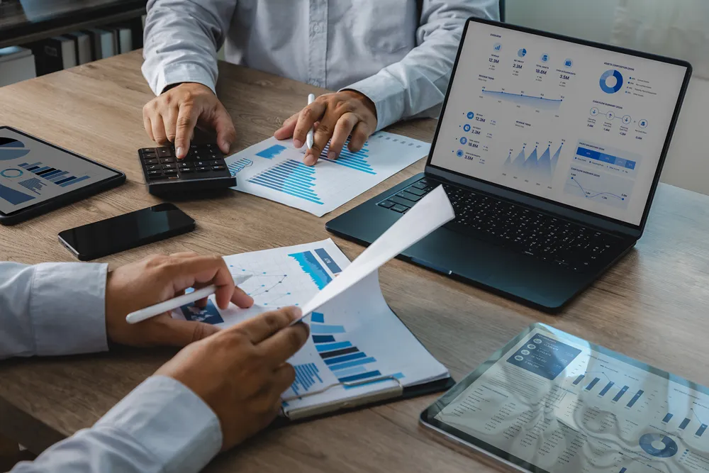 Business team reviewing accounting and financial reports with a calculator and dashboard during an office meeting.