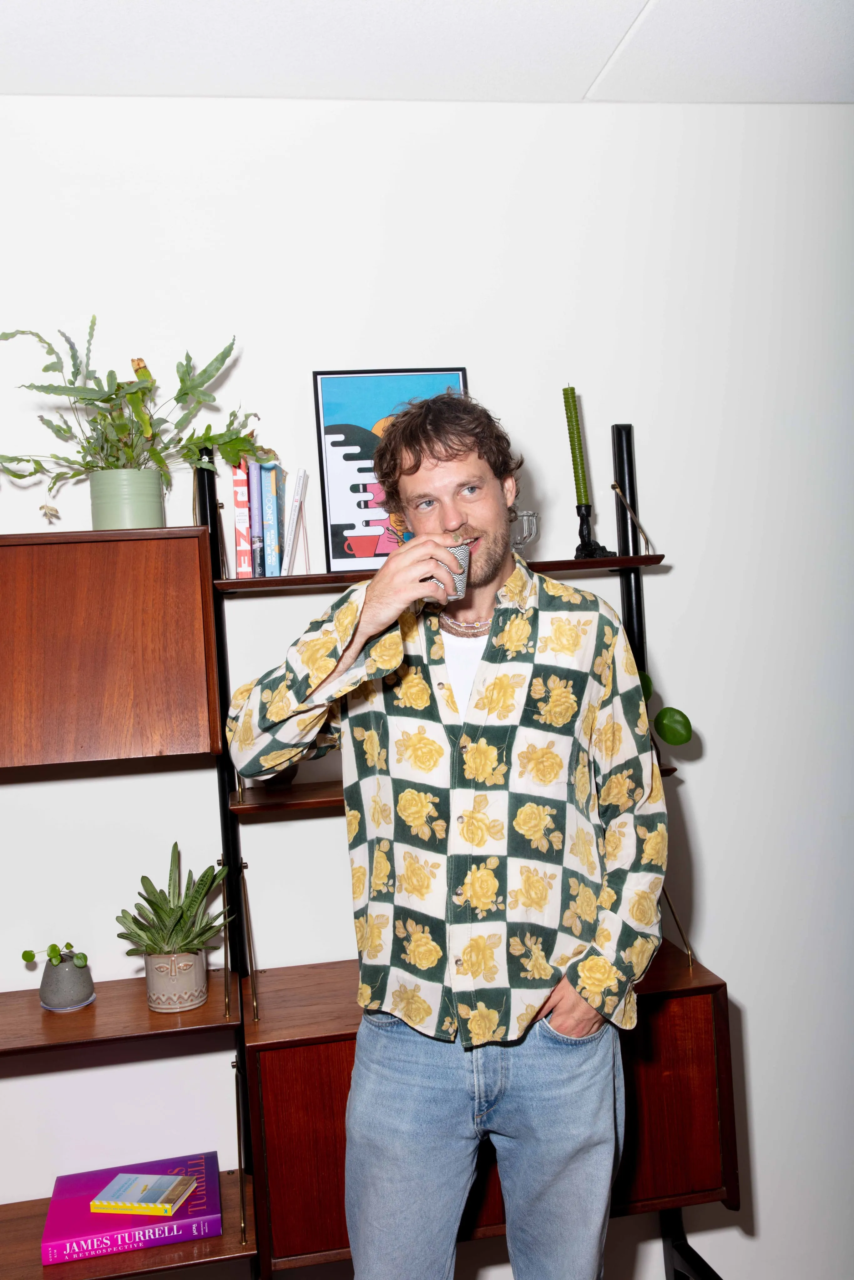 Foto van een man met een drankje in zijn hand voor een kast