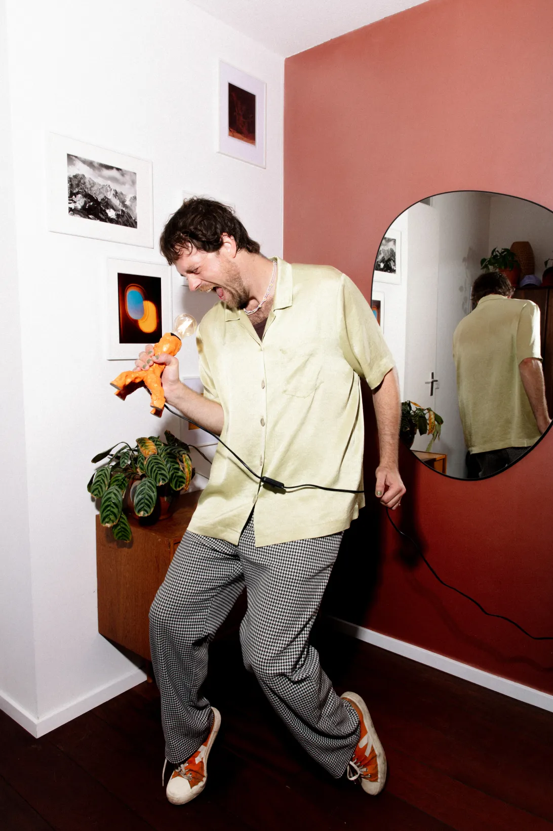 een foto van een man in een geel shirt die aan het zingen is in een lamp