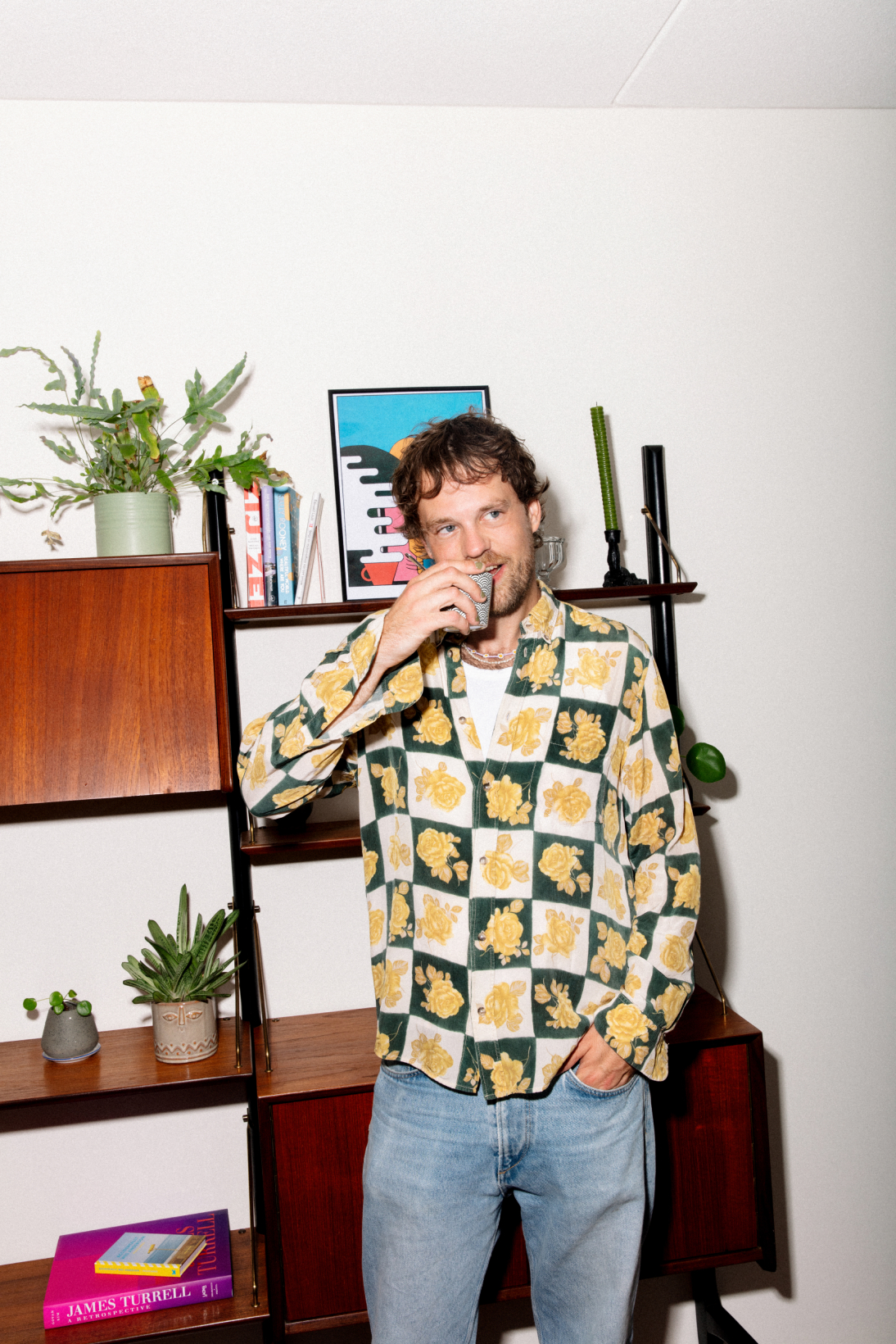 Foto van een man met een drankje in zijn hand voor een kast