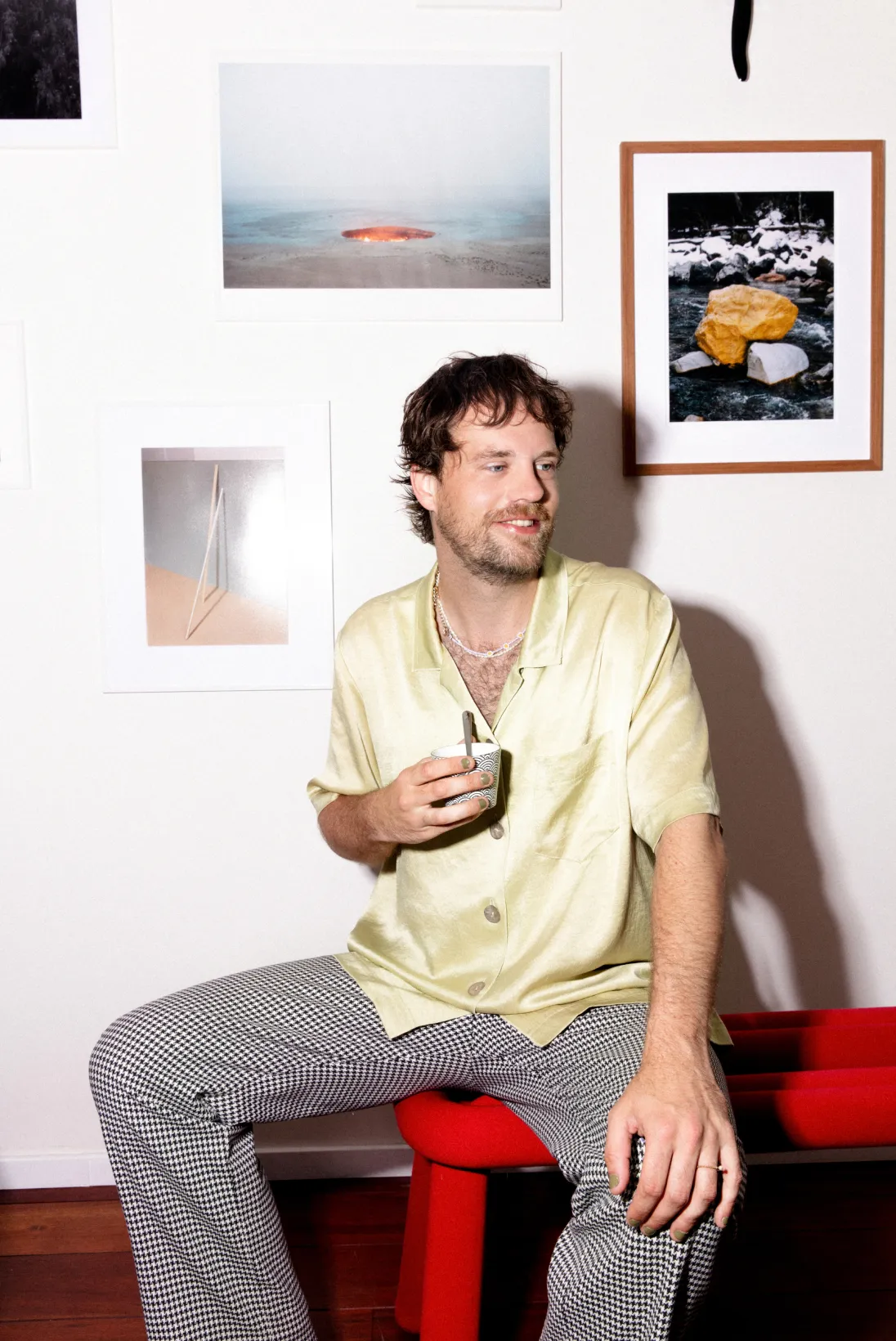 een foto van een man op een rode stoel met een drankje in zijn hand