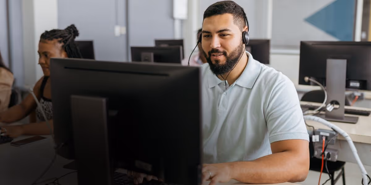 Customer Success team member providing support from the helpdesk, using headset and computer to assist fleet customers efficiently.