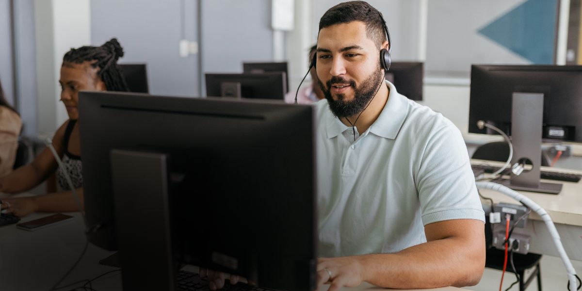 Customer Success team member providing support from the helpdesk, using headset and computer to assist fleet customers efficiently.