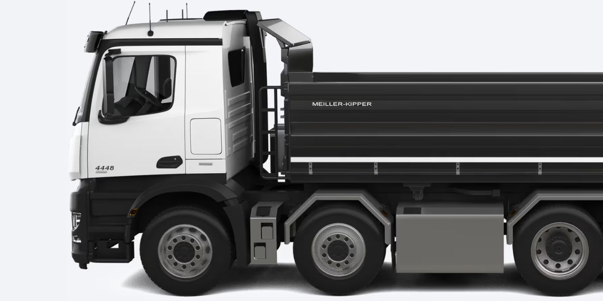 A cyclist wearing an orange jersey and black helmet is riding closely behind a large white refuse collection truck, appearing to be in a dangerous position directly behind the rear loading area.