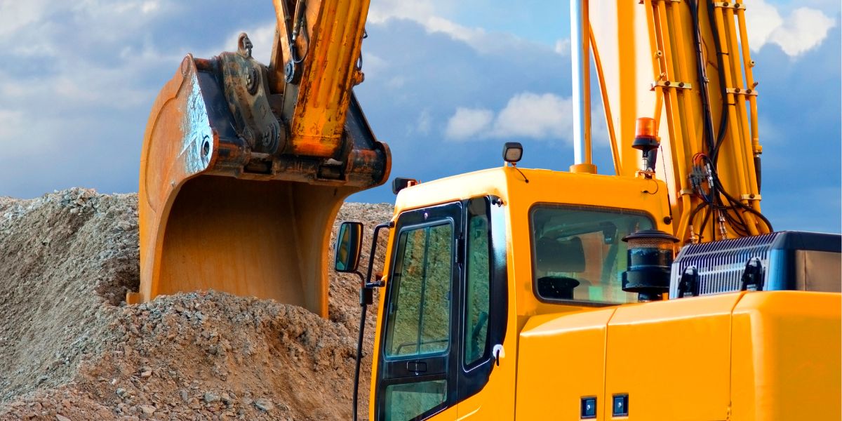A big yellow digger scooping stones of a big pile.