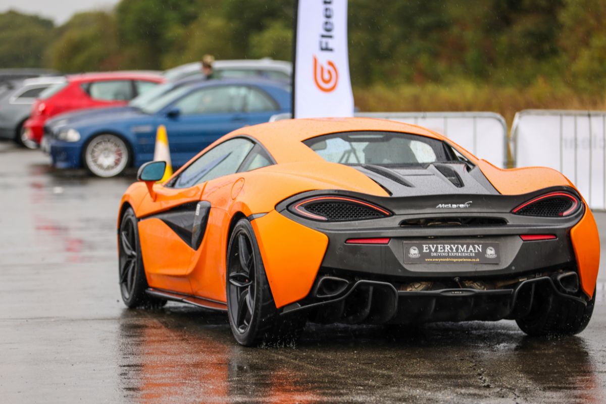 Orange Mclaren driving past Fleetclear flag