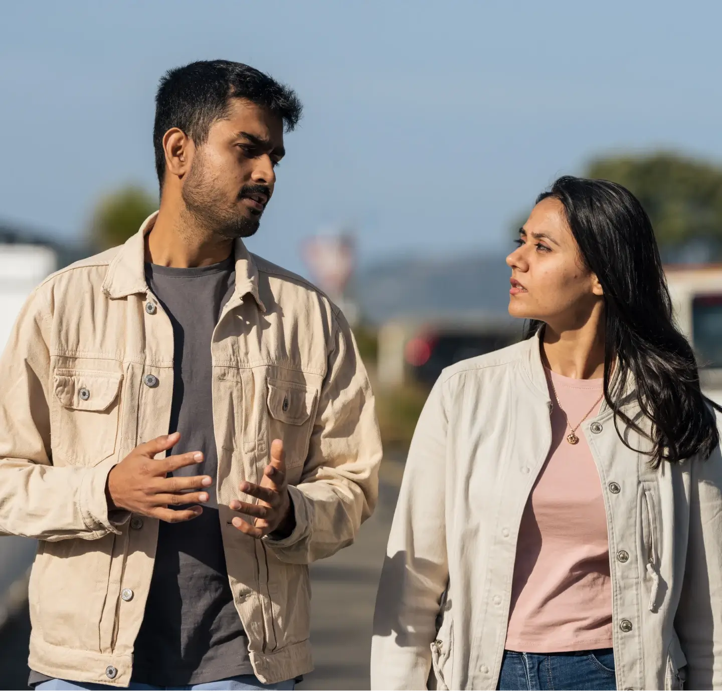 man and woman walking outdoors having conversation.