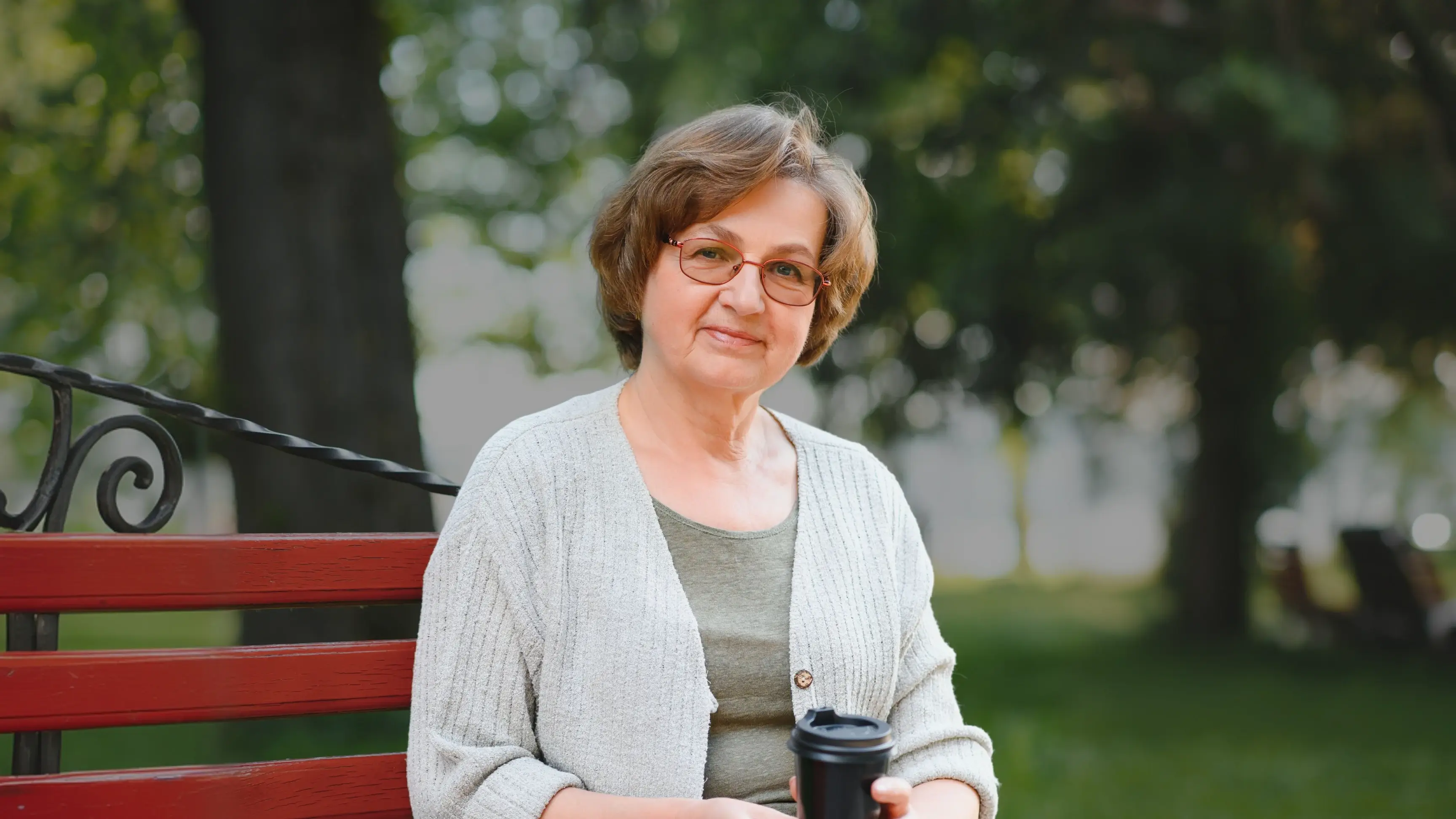 senior woman sitting on park bench smiling