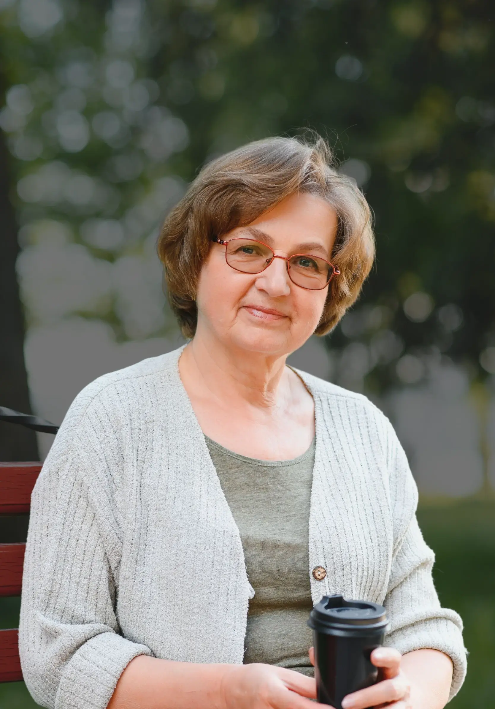 senior woman sitting on park bench smiling