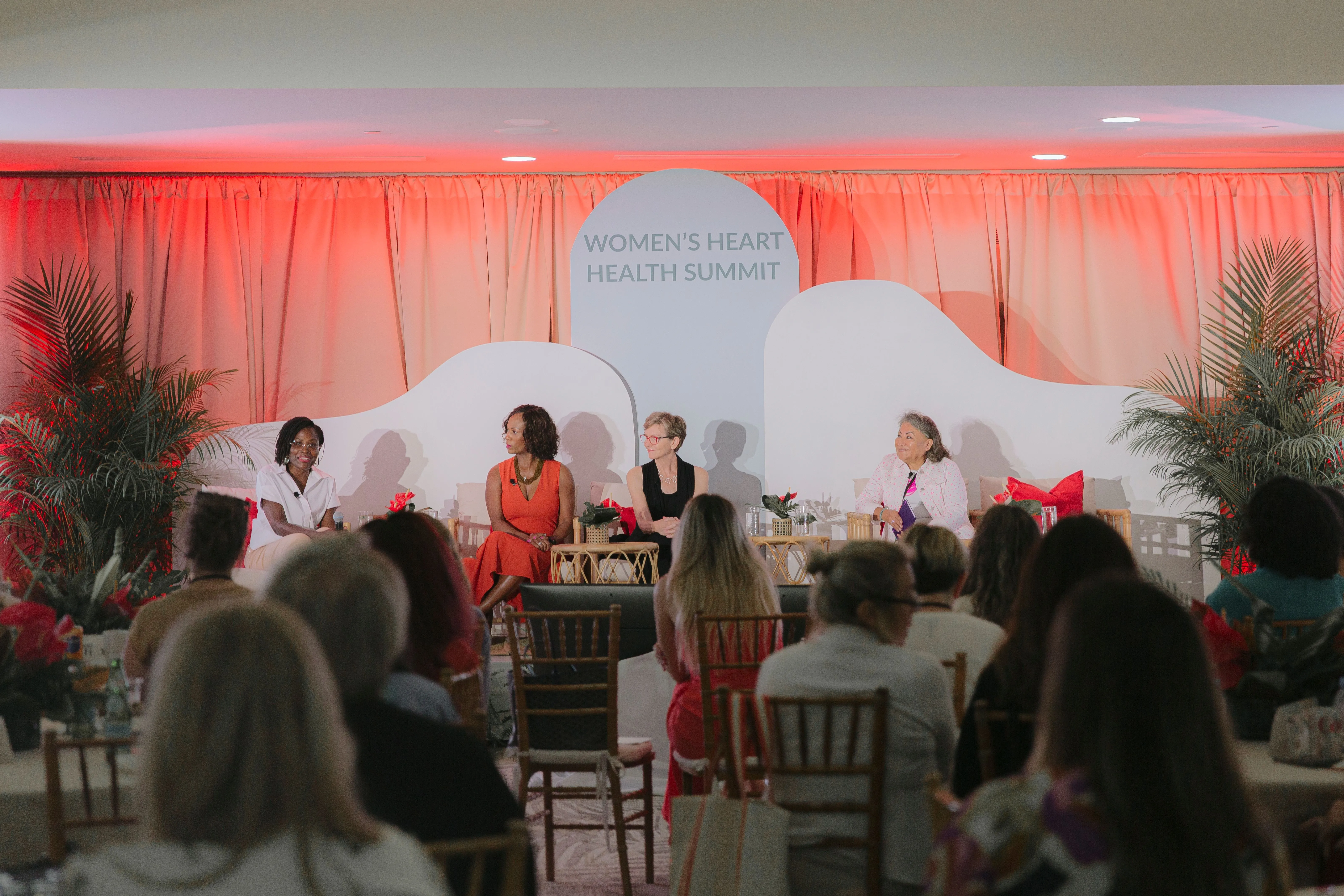 Panel of four women seated on stage at Women's Heart Health Summit with audience in foreground.