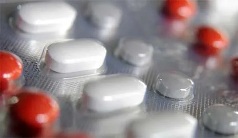 Close-up of white and red pills in blister packaging on a flat surface.