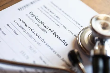 Close-up of an explanation of benefits document with a stethoscope resting on it.