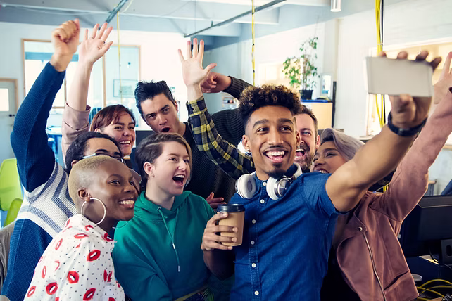 Eine Gruppe fröhlicher junger Menschen macht zusammen ein Selfie in einem hellen Raum.