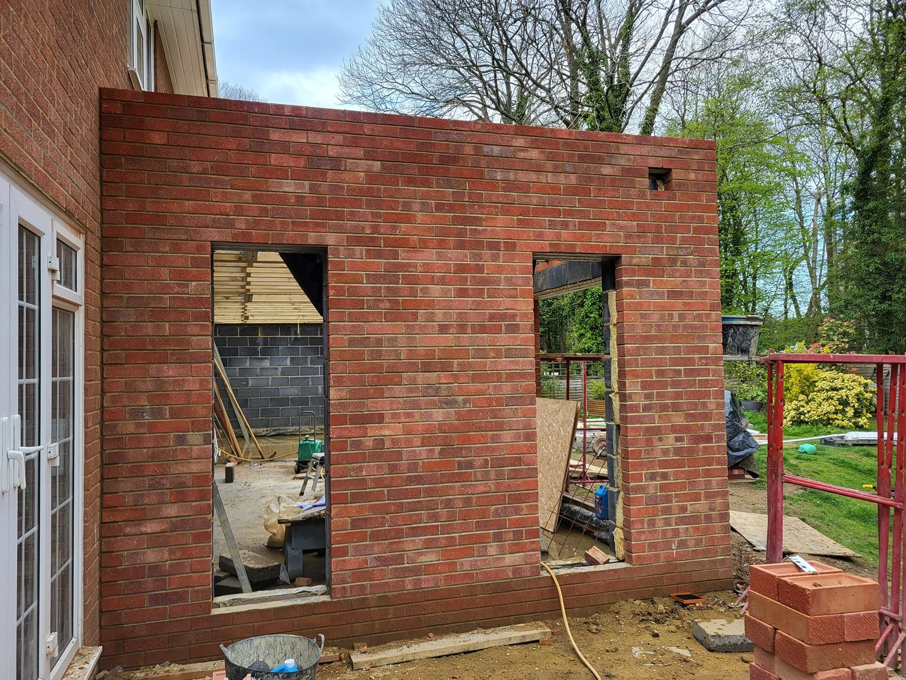 A single-storey rear extension in Hillingdon from the ground up: new drainage, insulated slab, cavity walls in matching brick and a timber warm roof with rooflights.