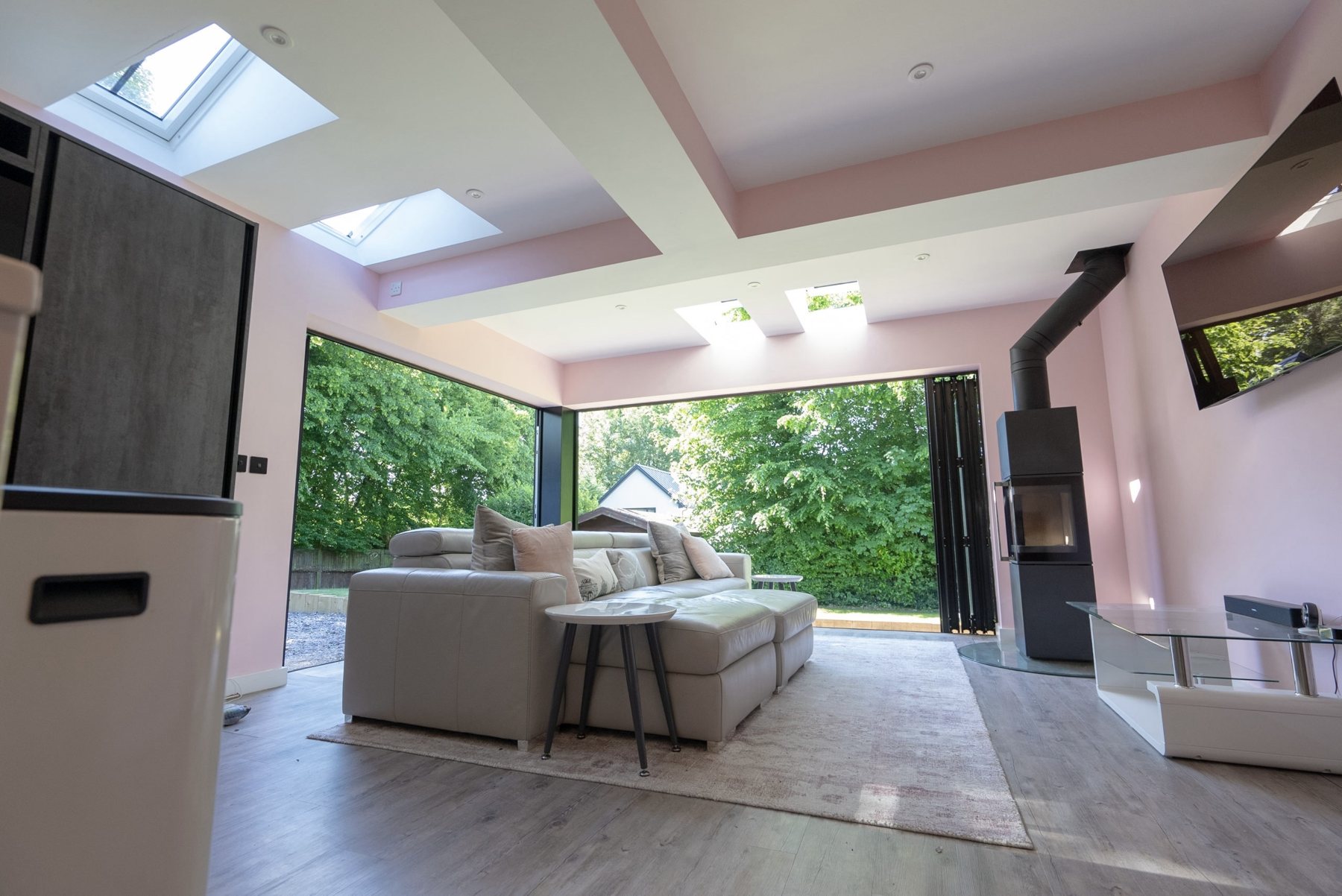 A rear extension with a vaulted ceiling, rooflights and a wall of bifold doors, fitted with a marble-topped island kitchen and a log burner at the heart of the living space.